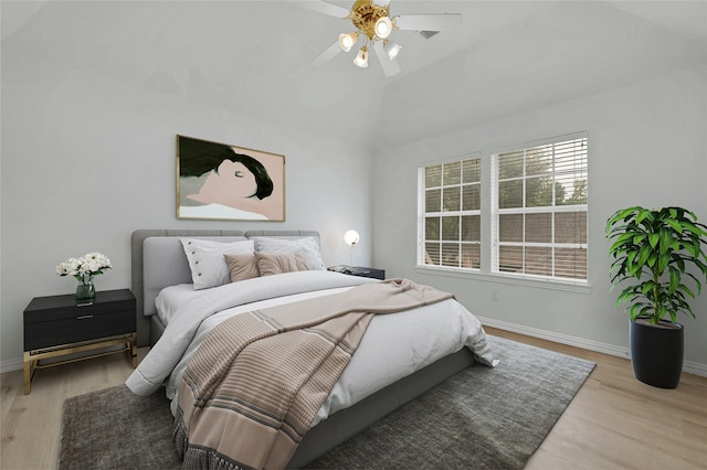 bedroom featuring baseboards, light wood finished floors, vaulted ceiling, and ceiling fan