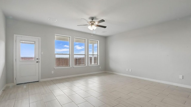 empty room featuring baseboards, a ceiling fan, and visible vents