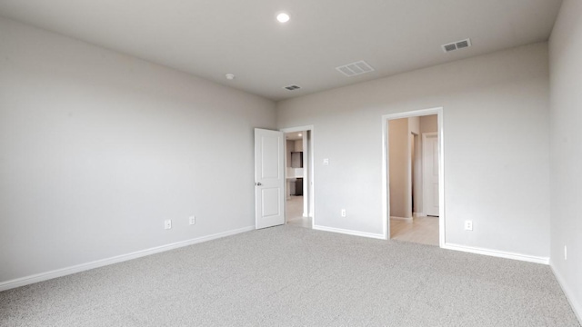 unfurnished room featuring baseboards, light colored carpet, and visible vents