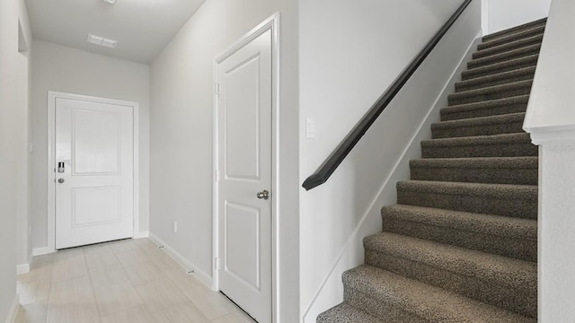 staircase featuring baseboards and visible vents