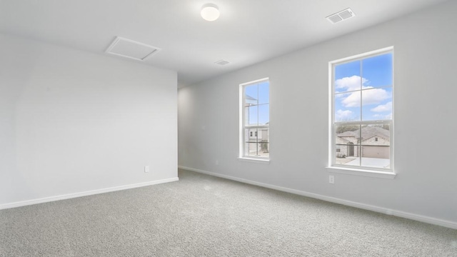 carpeted spare room with baseboards, attic access, and visible vents