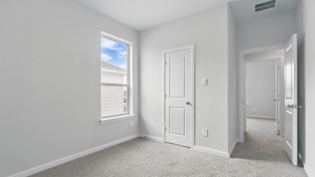unfurnished bedroom featuring light colored carpet, visible vents, and multiple windows