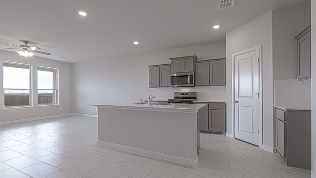 kitchen featuring visible vents, a ceiling fan, a sink, gray cabinetry, and stainless steel appliances