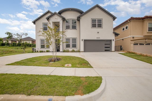 french country inspired facade featuring a garage, a front lawn, stucco siding, and driveway