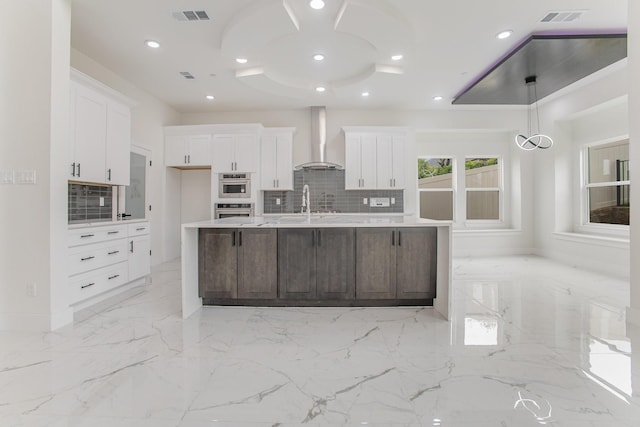 kitchen featuring visible vents, white cabinetry, and wall chimney range hood