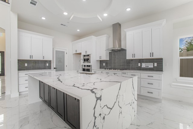 kitchen featuring visible vents, decorative backsplash, white cabinetry, and wall chimney range hood