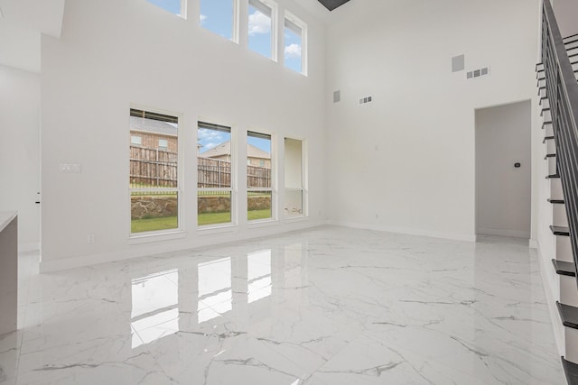 unfurnished living room featuring visible vents, marble finish floor, stairs, and a towering ceiling
