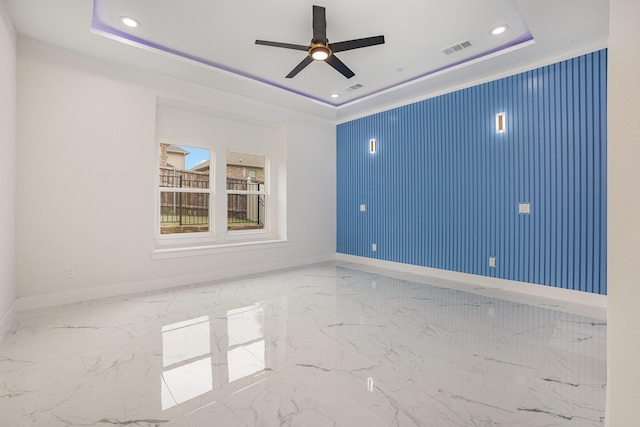 spare room featuring visible vents, a raised ceiling, and baseboards