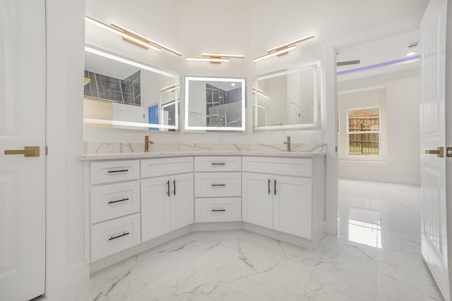bathroom with a sink, double vanity, marble finish floor, and walk in shower
