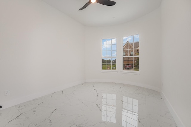 unfurnished room featuring baseboards, ceiling fan, and marble finish floor