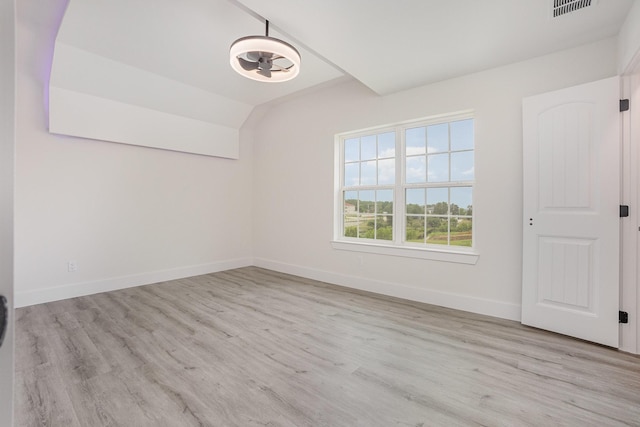 empty room with baseboards, lofted ceiling, wood finished floors, and visible vents