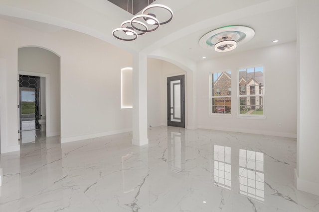 interior space featuring arched walkways, baseboards, recessed lighting, and marble finish floor