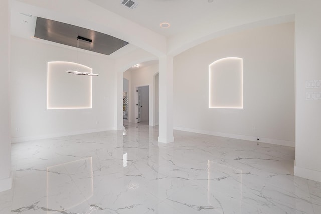unfurnished room featuring arched walkways, baseboards, visible vents, and marble finish floor