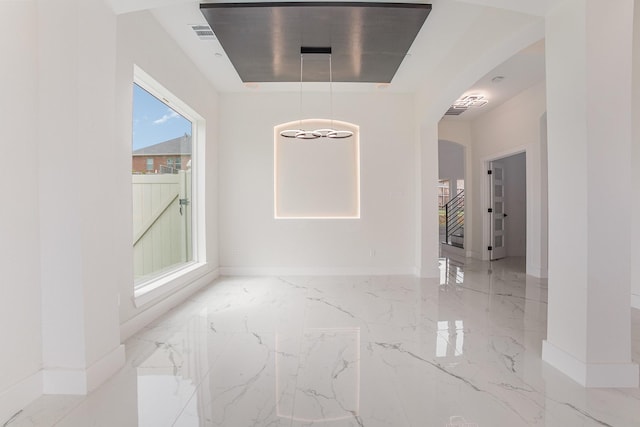 interior space featuring arched walkways, baseboards, and marble finish floor
