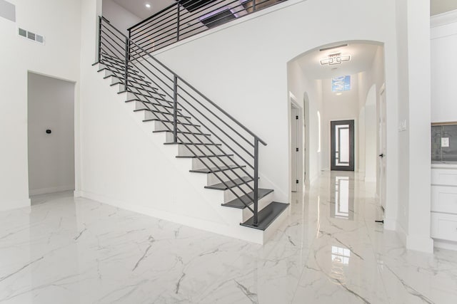 entryway featuring visible vents, arched walkways, marble finish floor, and a towering ceiling