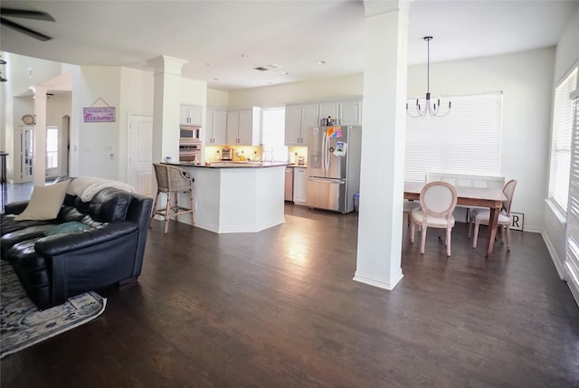 3301 Ski Lift Ct, Mckinney, TX 75070 - kitchen with stainless steel appliances, ornate columns, open floor plan, a chandelier, and dark wood-style flooring