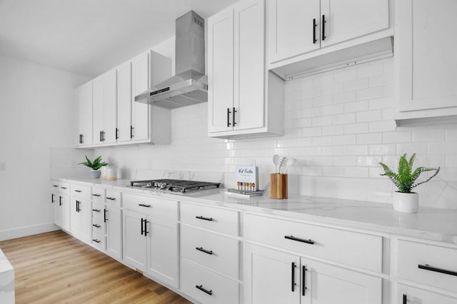 1922 Annex Ave, Dallas, TX 75204 - kitchen with wall chimney range hood, light stone counters, white cabinetry, stainless steel gas stovetop, and backsplash