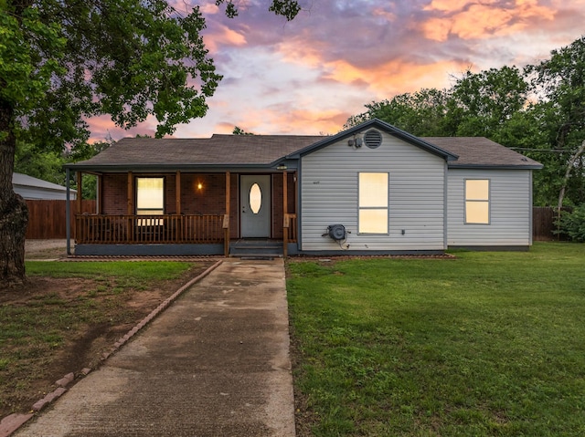 view of front of home featuring a porch, fence, driveway, and a front yard
