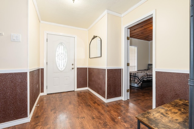 entrance foyer featuring ornamental molding, wood finished floors, and a wainscoted wall