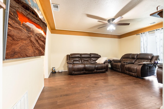 living area with a textured ceiling, ceiling fan, visible vents, and wood finished floors