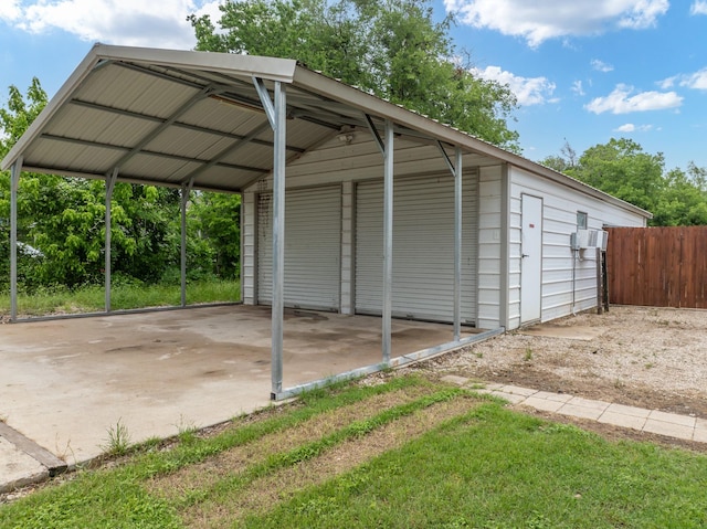 view of parking / parking lot with fence and a carport