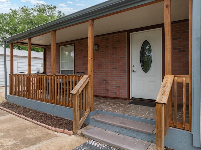 property entrance with covered porch and brick siding