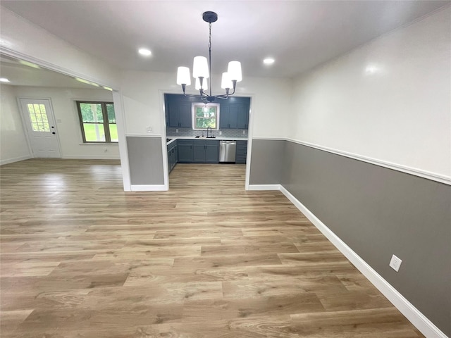 unfurnished dining area with a chandelier, a sink, baseboards, light wood finished floors, and recessed lighting