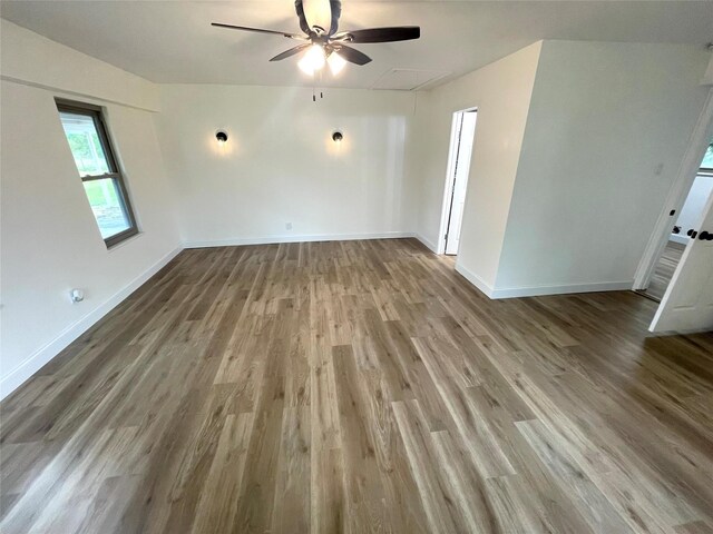 spare room with attic access, wood finished floors, ceiling fan, and baseboards