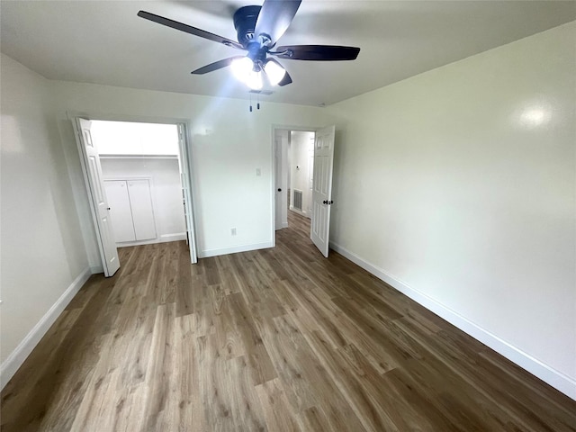unfurnished bedroom featuring wood finished floors, baseboards, a closet, and a ceiling fan