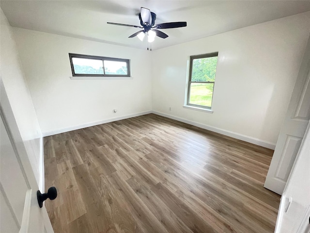 unfurnished room with wood finished floors, a ceiling fan, and baseboards