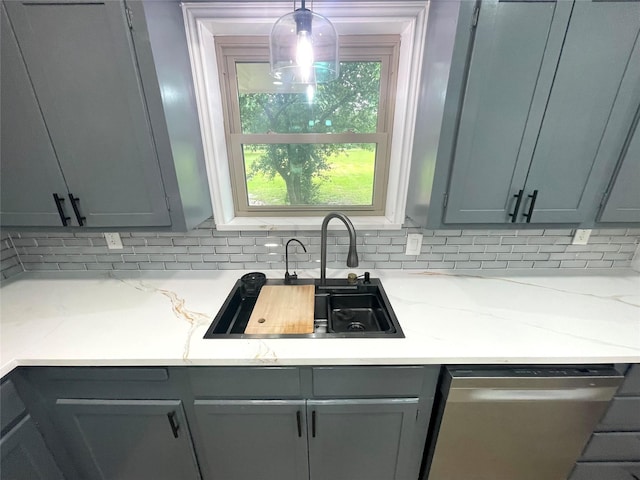 kitchen with stainless steel dishwasher, a sink, decorative backsplash, and gray cabinets