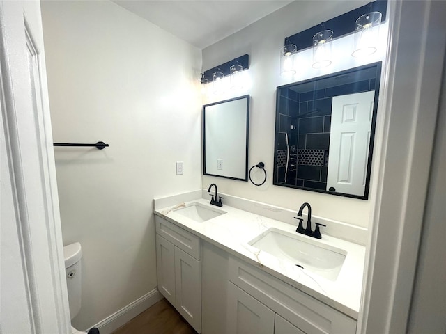 bathroom with baseboards, toilet, and double vanity