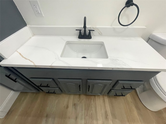bathroom with toilet, wood finished floors, and vanity