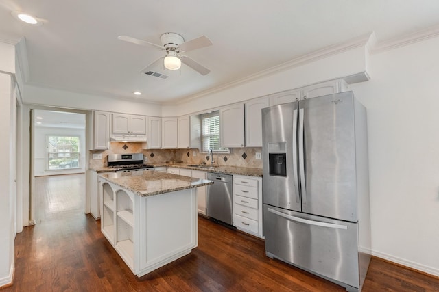 kitchen featuring visible vents, crown molding, appliances with stainless steel finishes, a sink, and under cabinet range hood