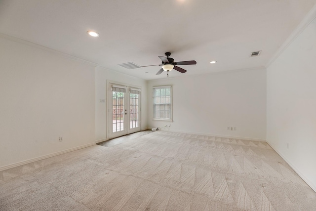 empty room featuring light colored carpet, a ceiling fan, visible vents, and ornamental molding