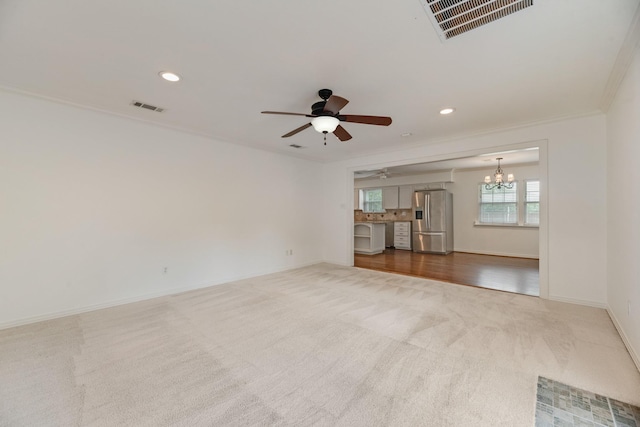 carpeted empty room with visible vents, crown molding, baseboards, and ceiling fan with notable chandelier