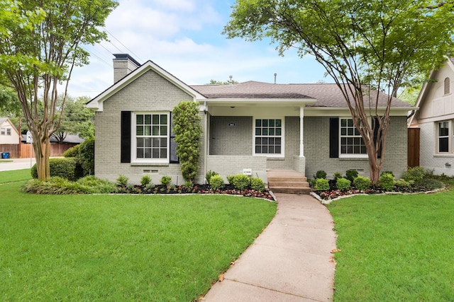 ranch-style home with brick siding, a chimney, and a front lawn