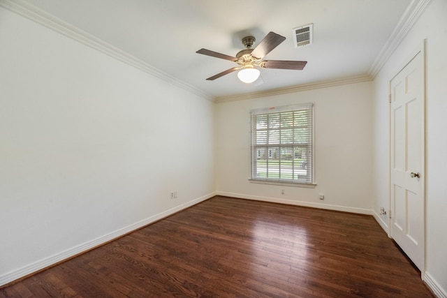 empty room featuring visible vents, dark wood finished floors, and crown molding
