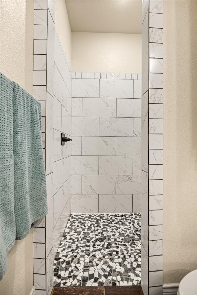 bathroom featuring toilet and a tile shower