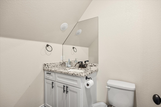bathroom with vanity, lofted ceiling, and toilet
