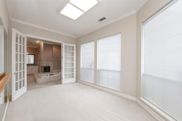 interior space featuring crown molding, a glass covered fireplace, french doors, and visible vents