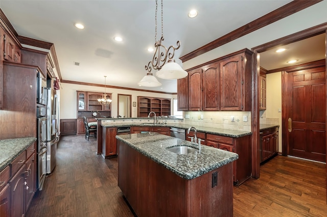 kitchen featuring a sink, a peninsula, crown molding, and a kitchen island with sink