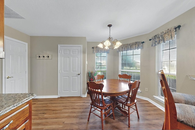 dining space featuring light wood-style floors, baseboards, and a notable chandelier