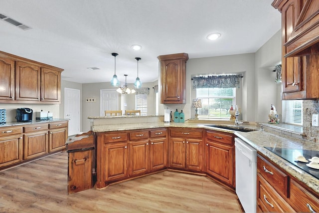 kitchen featuring visible vents, light wood-type flooring, brown cabinets, dishwasher, and a sink