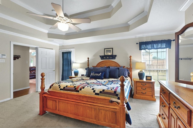 bedroom with a ceiling fan, light colored carpet, ornamental molding, and a raised ceiling