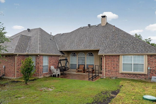 back of house with brick siding, a chimney, a patio area, and roof with shingles