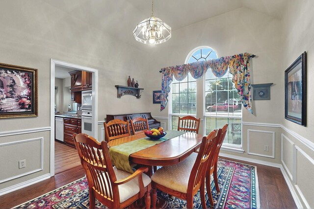 dining area featuring wainscoting, vaulted ceiling, dark wood finished floors, and a notable chandelier