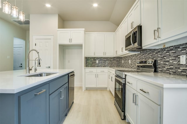 kitchen with a sink, appliances with stainless steel finishes, blue cabinets, and white cabinetry