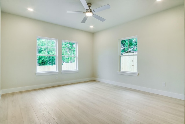 empty room featuring baseboards, ceiling fan, a wealth of natural light, and light wood-style flooring