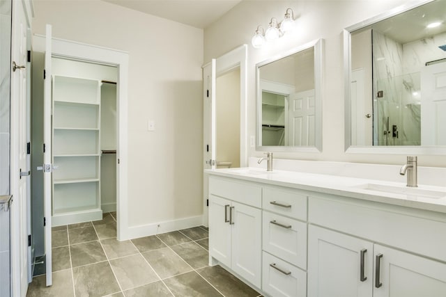 bathroom featuring a sink, a marble finish shower, double vanity, and a spacious closet